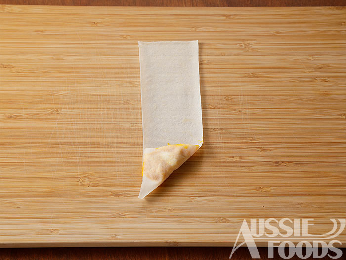 縦に三等分に切った春巻きの手前側に塩こしょうで味つけし、クリームチーズを加え混ぜたかぼちゃをのせ三角に折り、そのまま上に向かって畳んでいく。