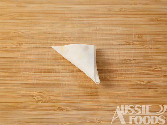 縦に三等分に切った春巻きの手前側に塩こしょうで味つけし、クリームチーズを加え混ぜたかぼちゃをのせ三角に折り、そのまま上に向かって畳んでいき余ったところは水（分量外）をつけて留める。
